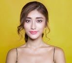 Beautiful portrait of a woman with elegant hairstyle on a vibrant yellow background.